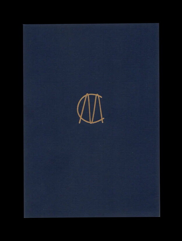 Minimalist book cover with a deep blue background and a small gold monogram-like symbol centered on the page. No imagery beyond the emblem.