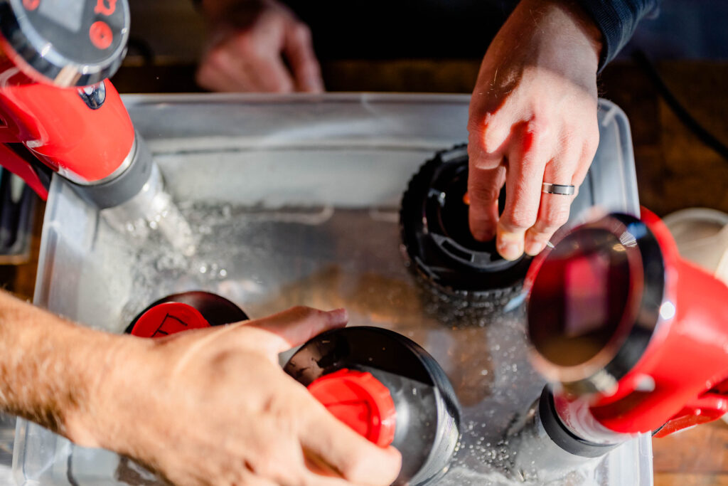 Hands putting canisters into liquid.