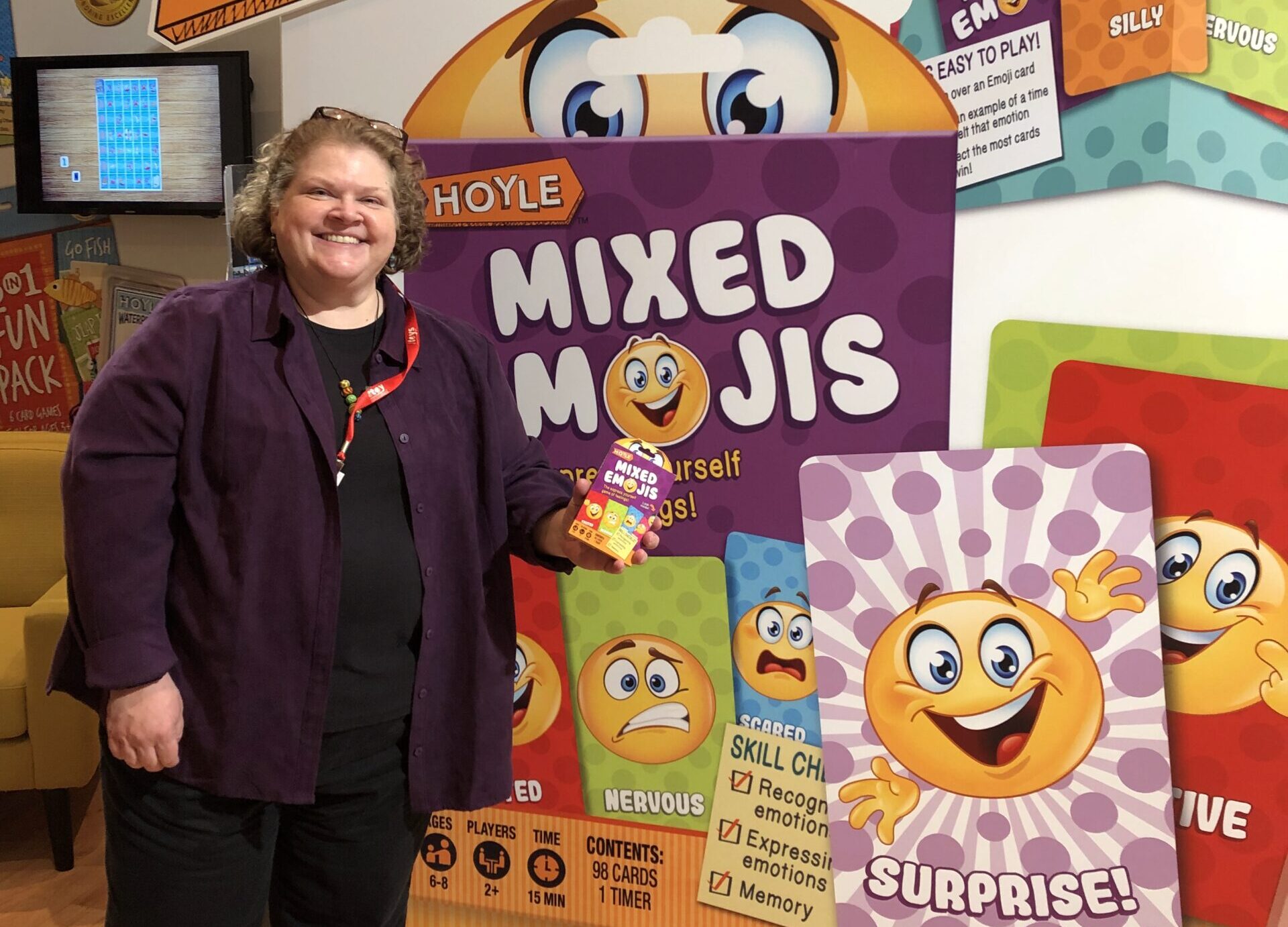 A light skinned woman standing next to a large colorful display.
