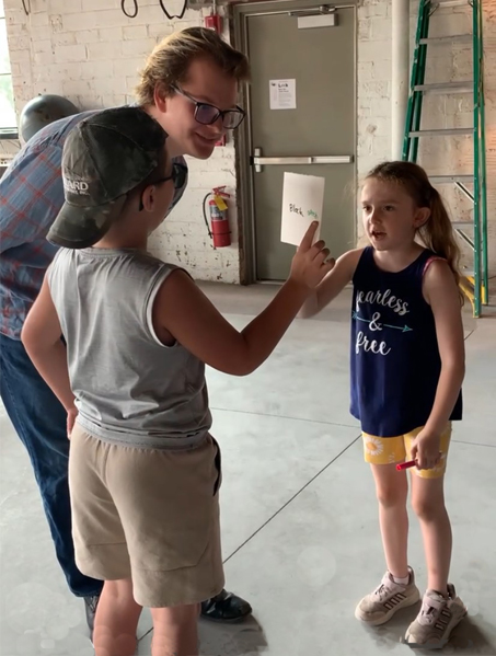 A young adult interacting with two young children.