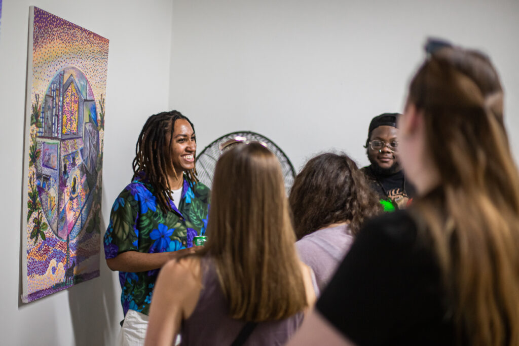 A group of people talking in front of a colorful abstract painting.