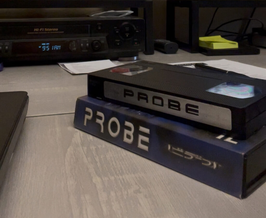 Two VHS tapes stacked next to a VHS stereo player.