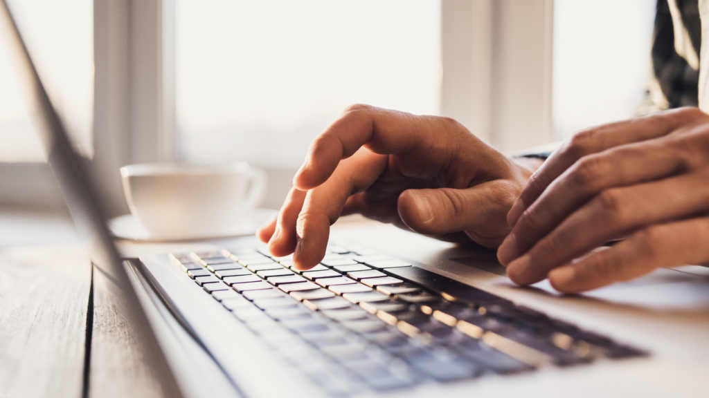 Two hands type on a laptop keyboard
