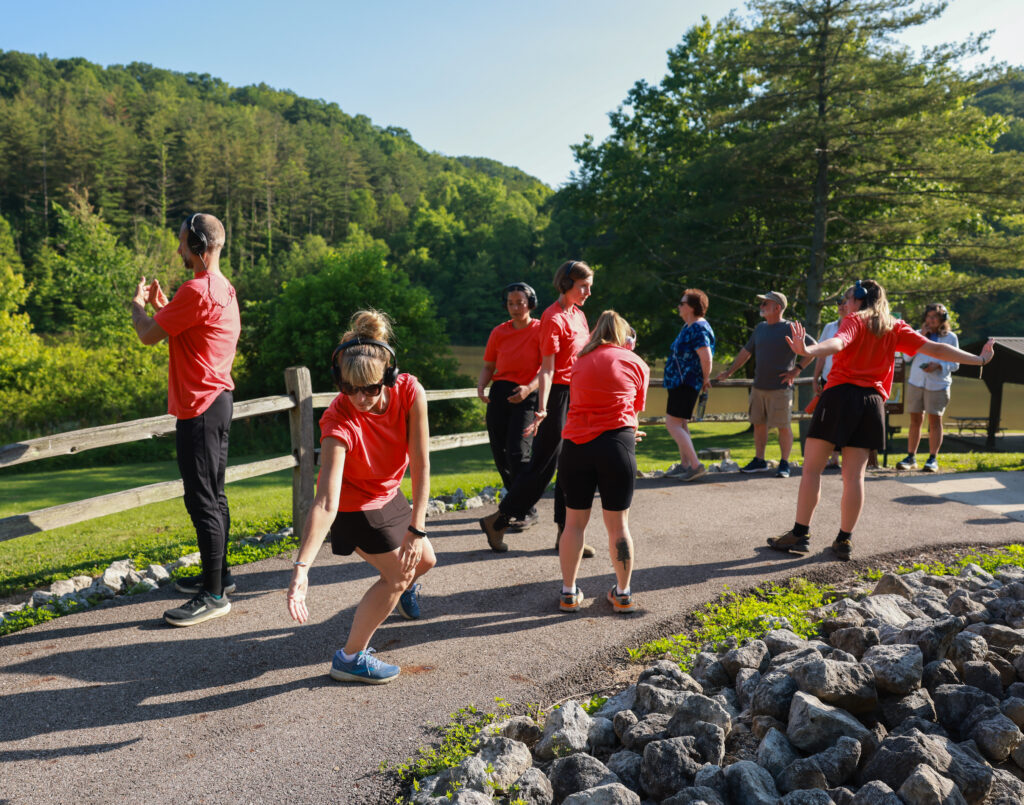 People standing at an outdoor trail. Some of them are stretching their arms and legs.