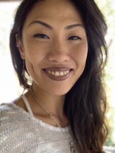 Headshot of a smiling Asian woman of medium skin tone with dark hair