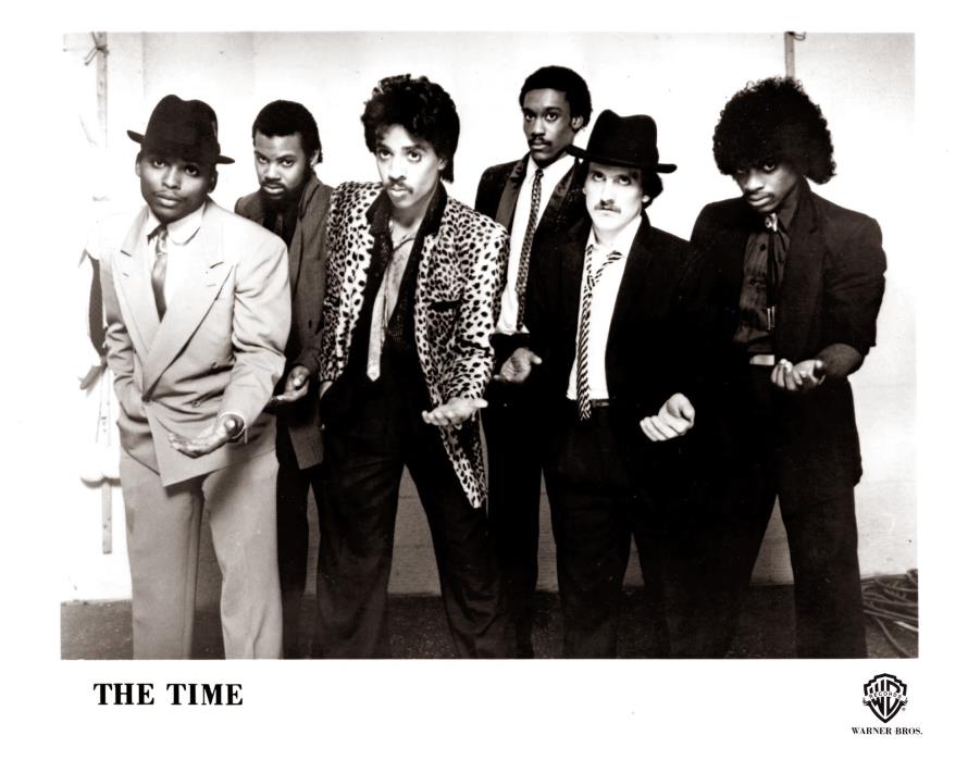 A black and white archival photo of six people standing next to each other and posing with each of them holding a hand out.