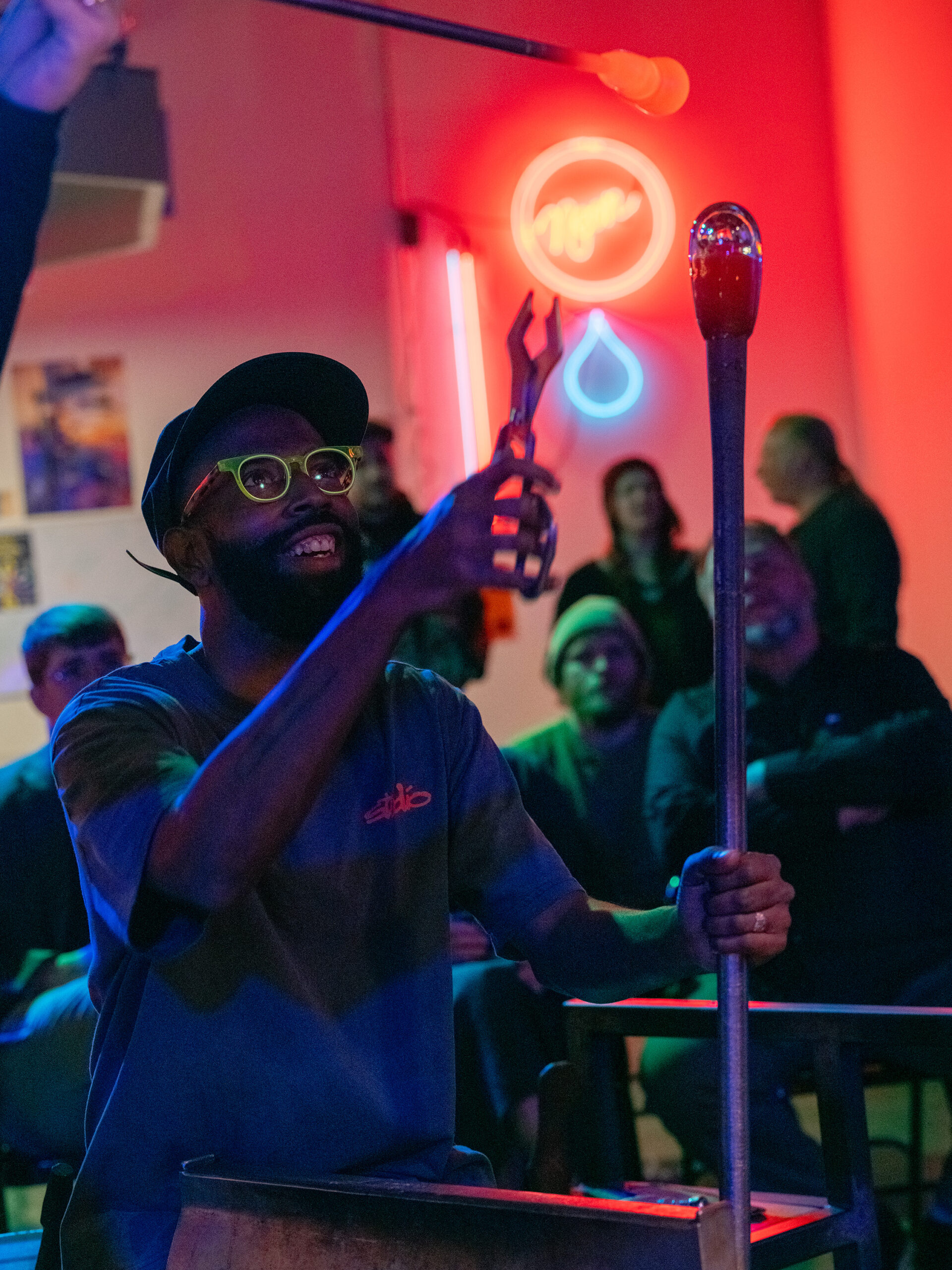 Glass artists handling their work in dramatic lighting
