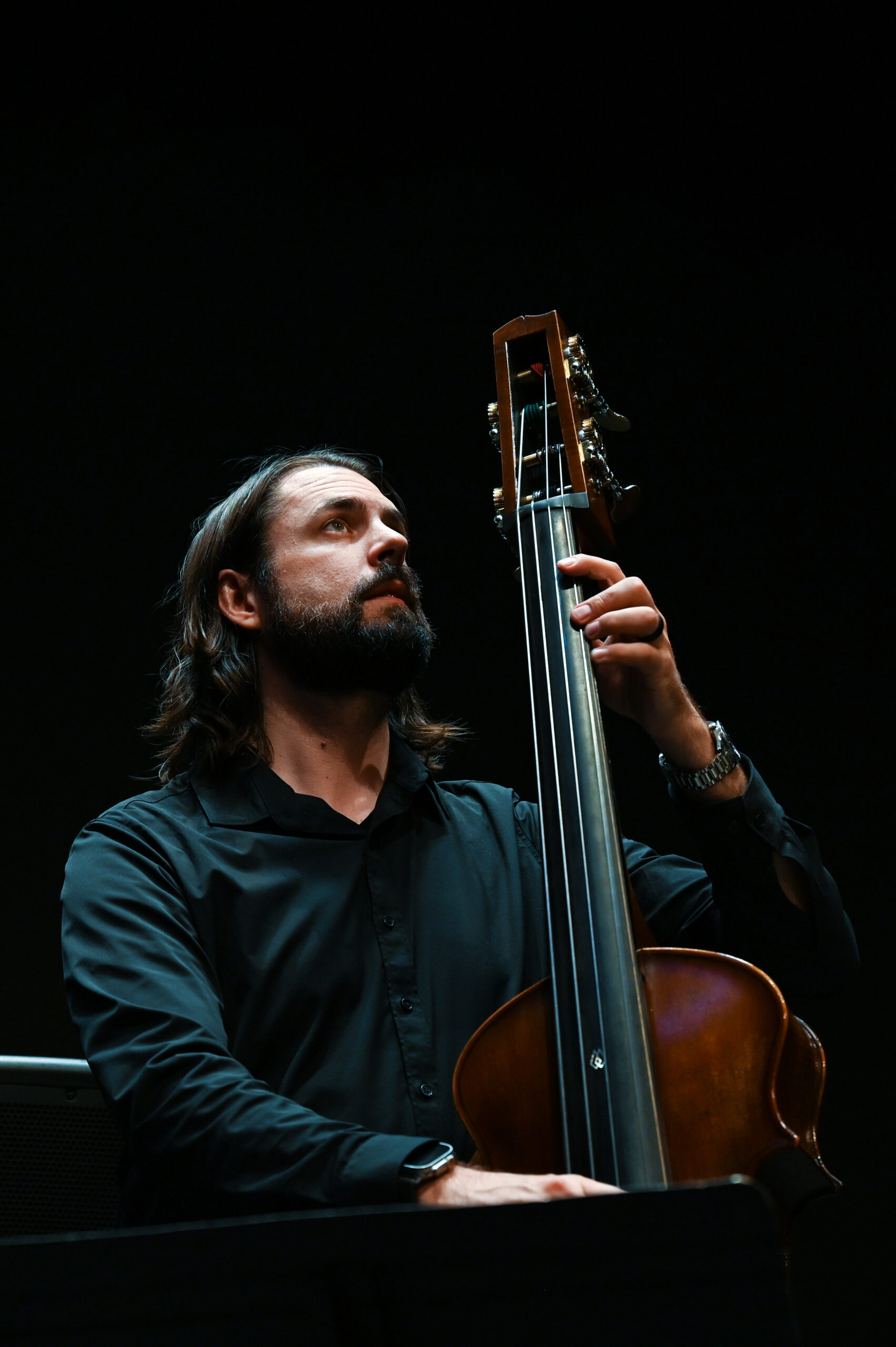 A white man with long hair plays the bass