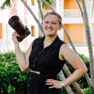 Headshots of smiling person in Black dress holding a camera with other hand on hip.