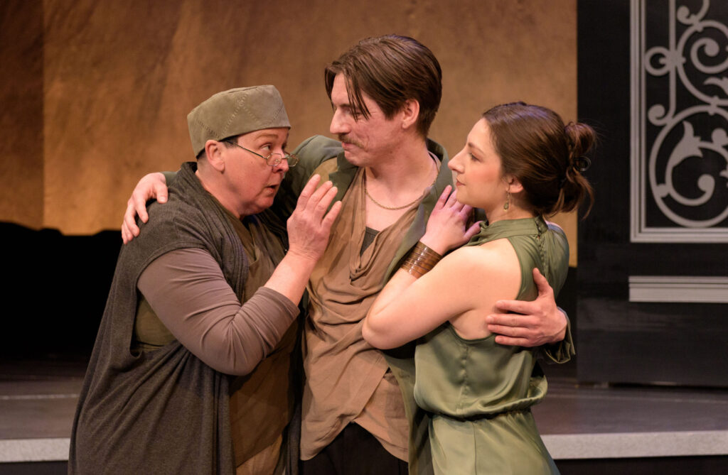 Three people embrace as the person on the left speaks and the other two pay attention.