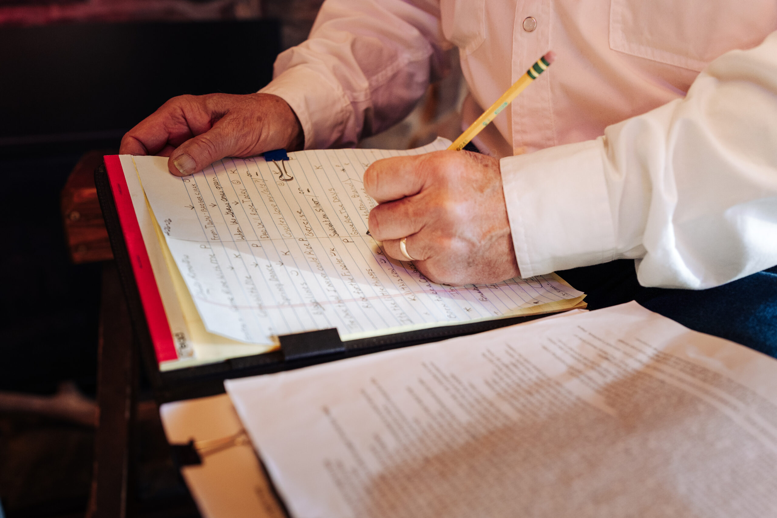 A person writing on a lined sheet of paper.