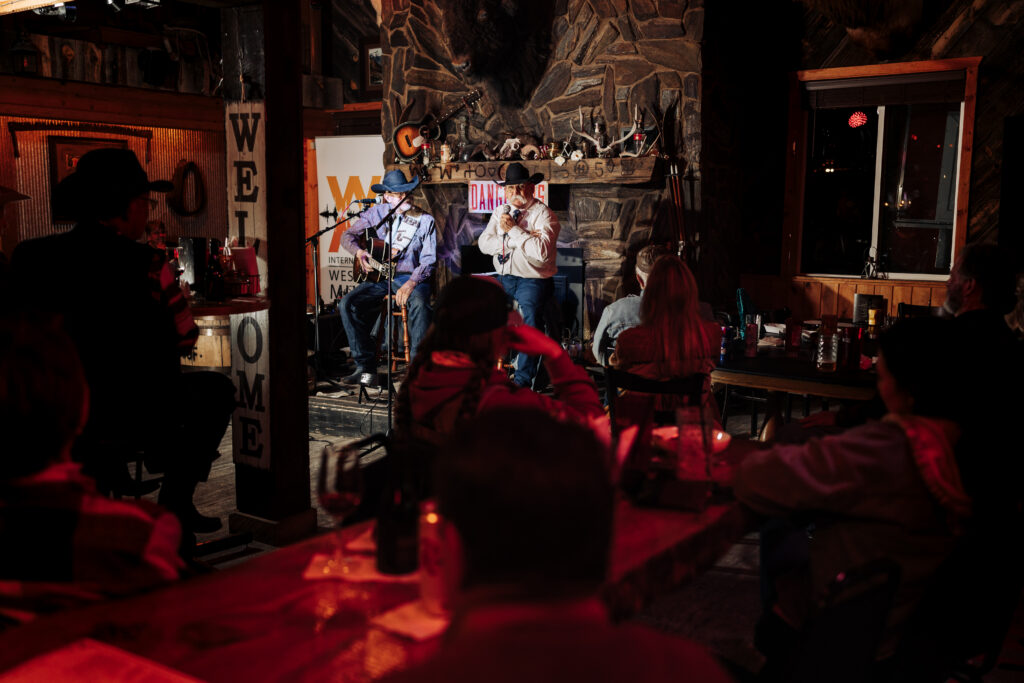 An audience at a bar watching two people perform on stage.
