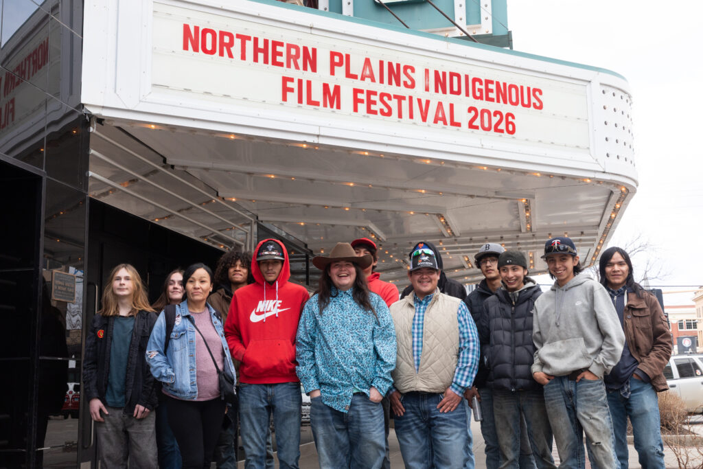 A group of people standing under a marquee reading Northern Plains Indigenous Film Festival 2026 and a large green sign reading Fargo.