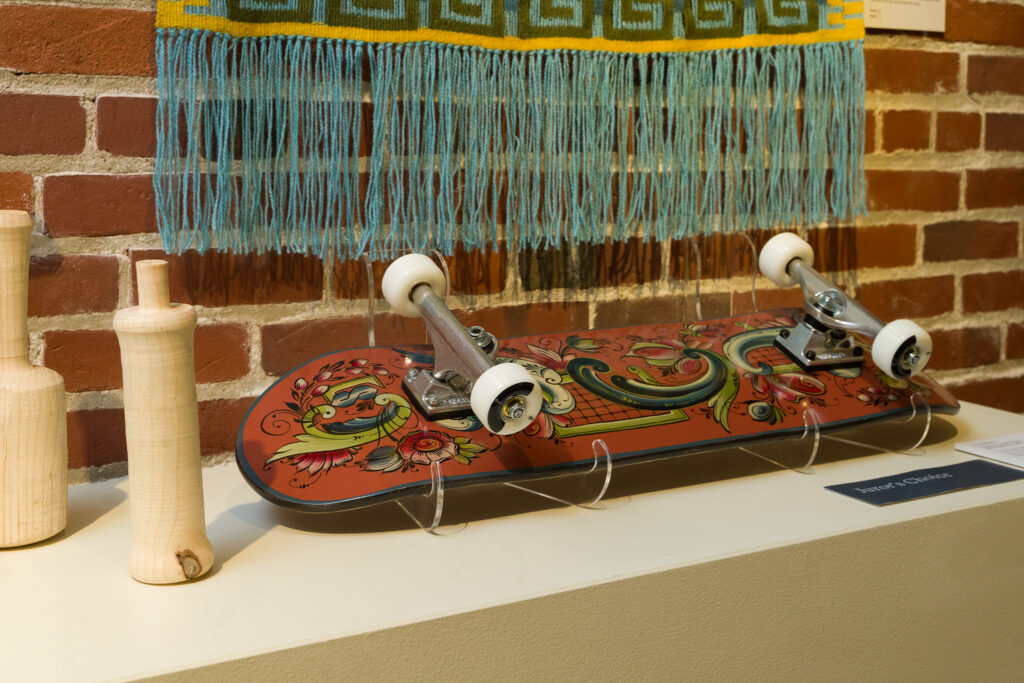 A hand painted skateboard displayed on a white pedestal