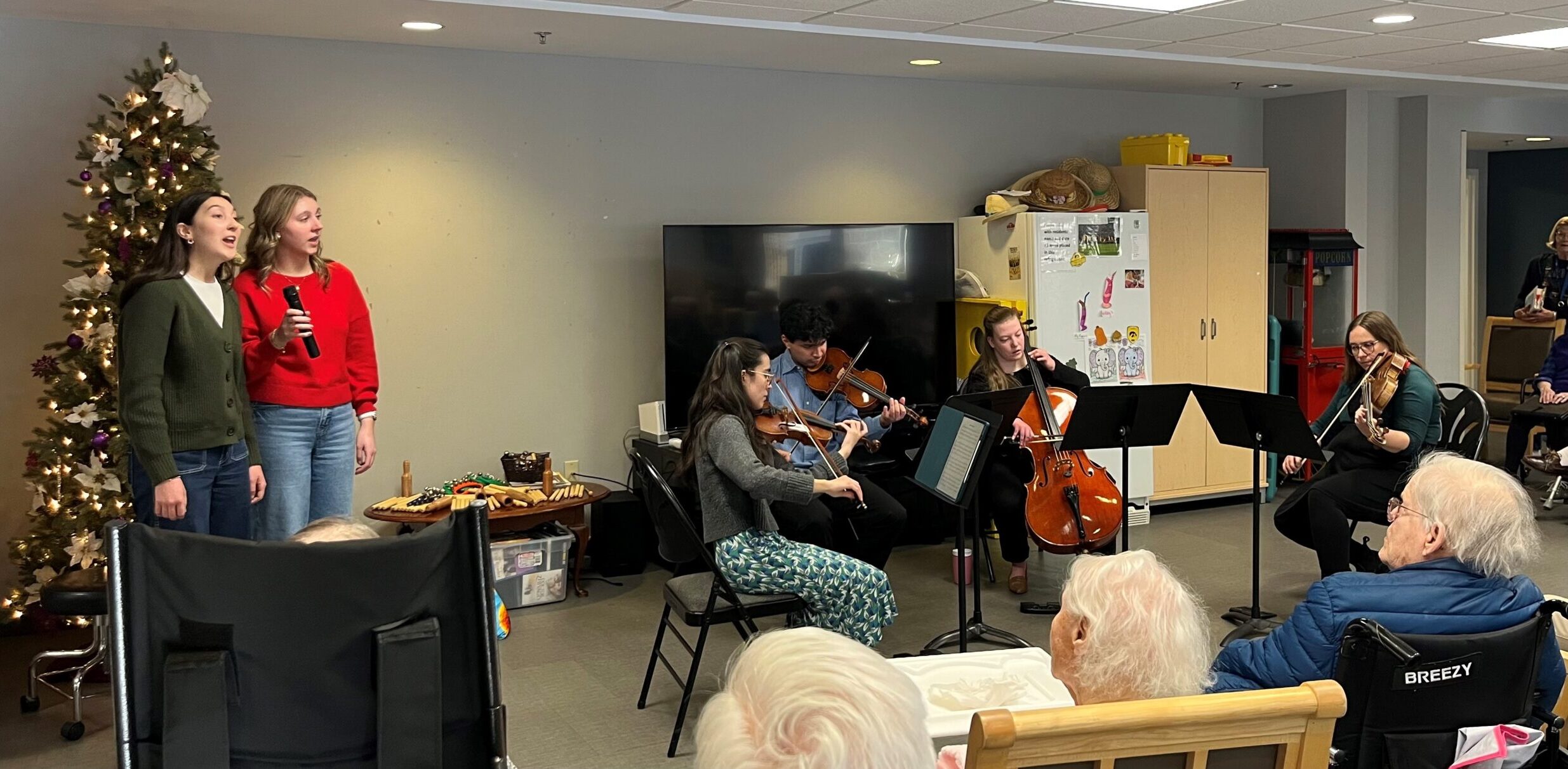 Performers singing and playing instruments for an audience of elderly people