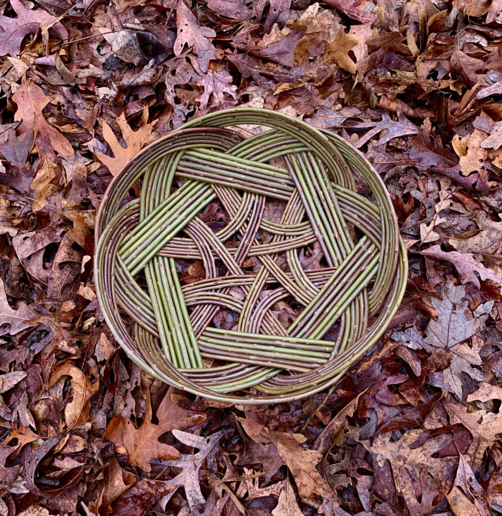 An intricate, decorative basket on a ground of leaves.