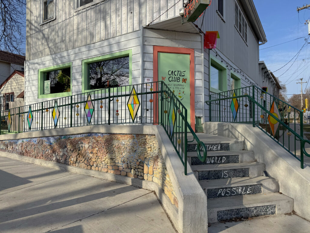 A building with an artfully-made concrete accessibility ramp with a stone mosaic and glasswork on the railings.