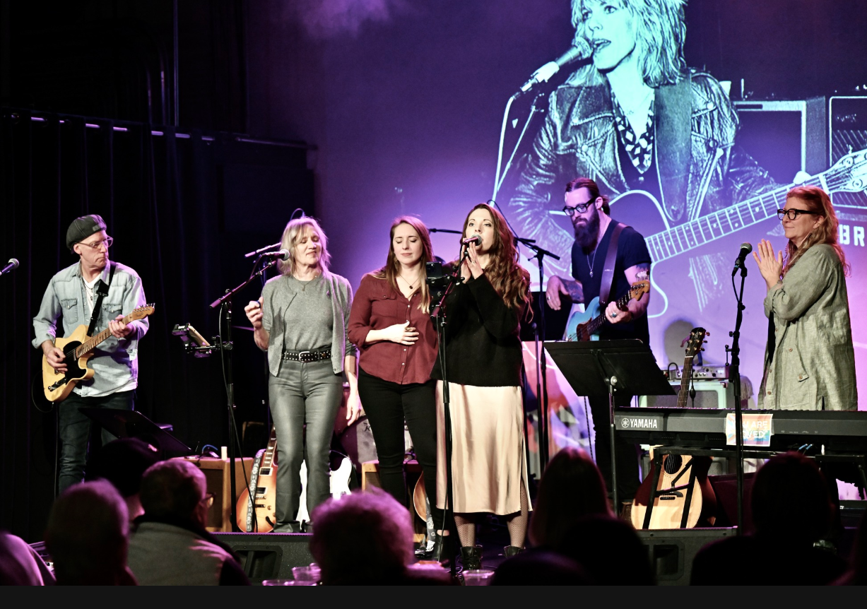 Six musicians on stage performing.