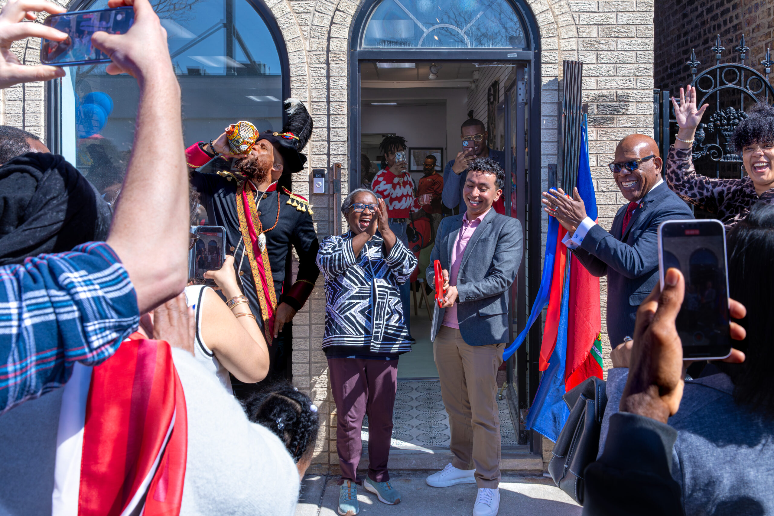People standing in front of a door of a building. They're emoting, clapping, and celebrating with smiles on their faces.