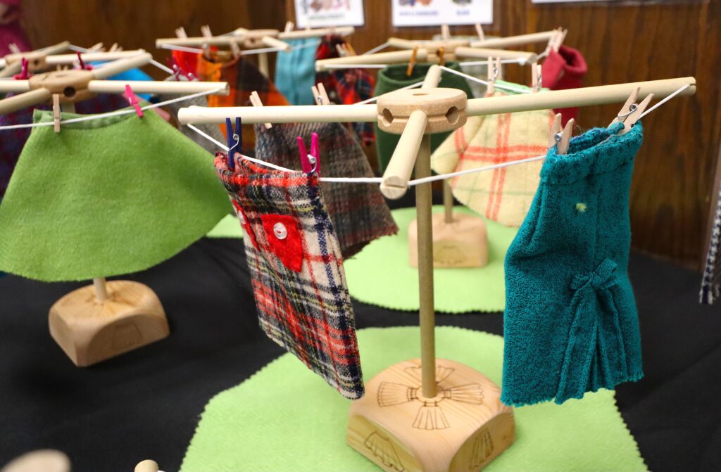 Miniature wool skirts hanging on Tinker Toy clotheslines.