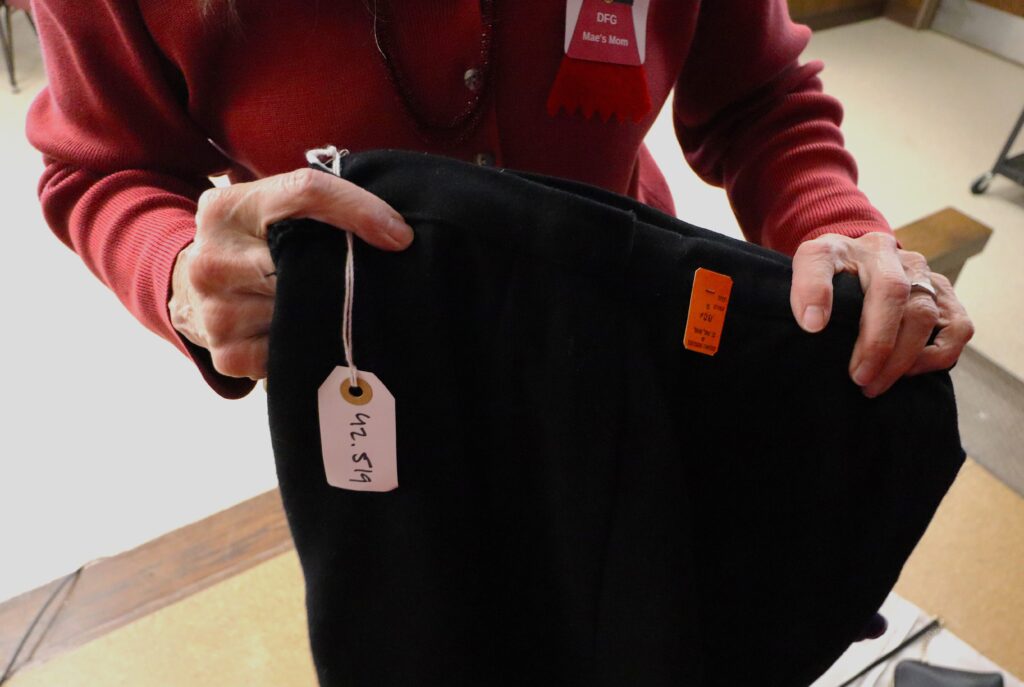 Two light skinned hands holding a skirt with tags on it.