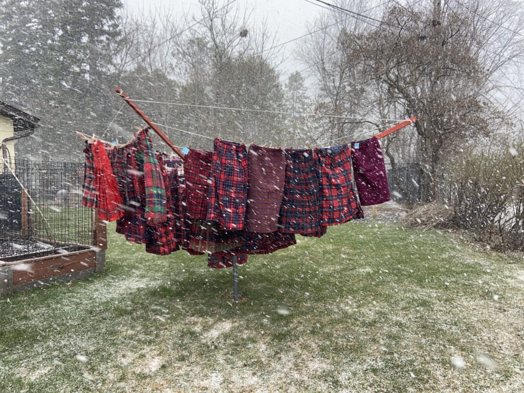 Red woolen skirts on a clothesline in the snow.