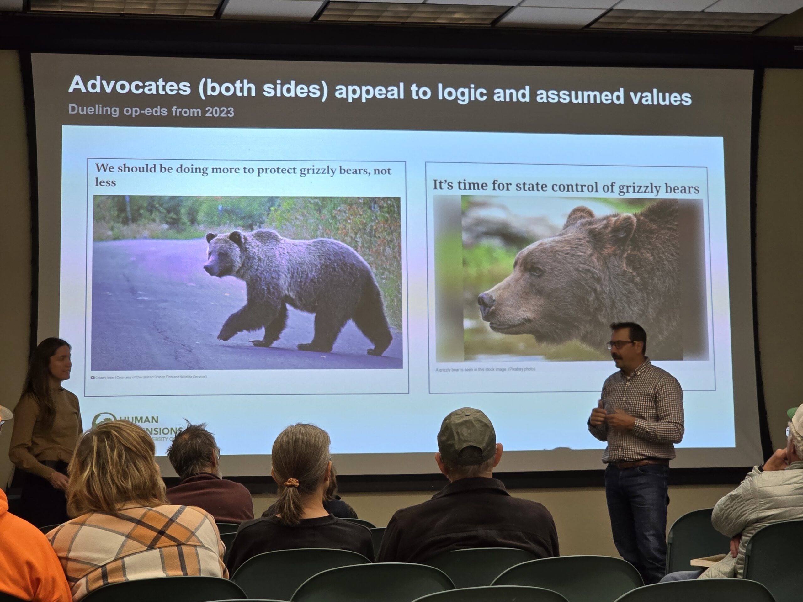 A person speaking to an audience as they have a projected slideshow in the background showing imagery of bears
