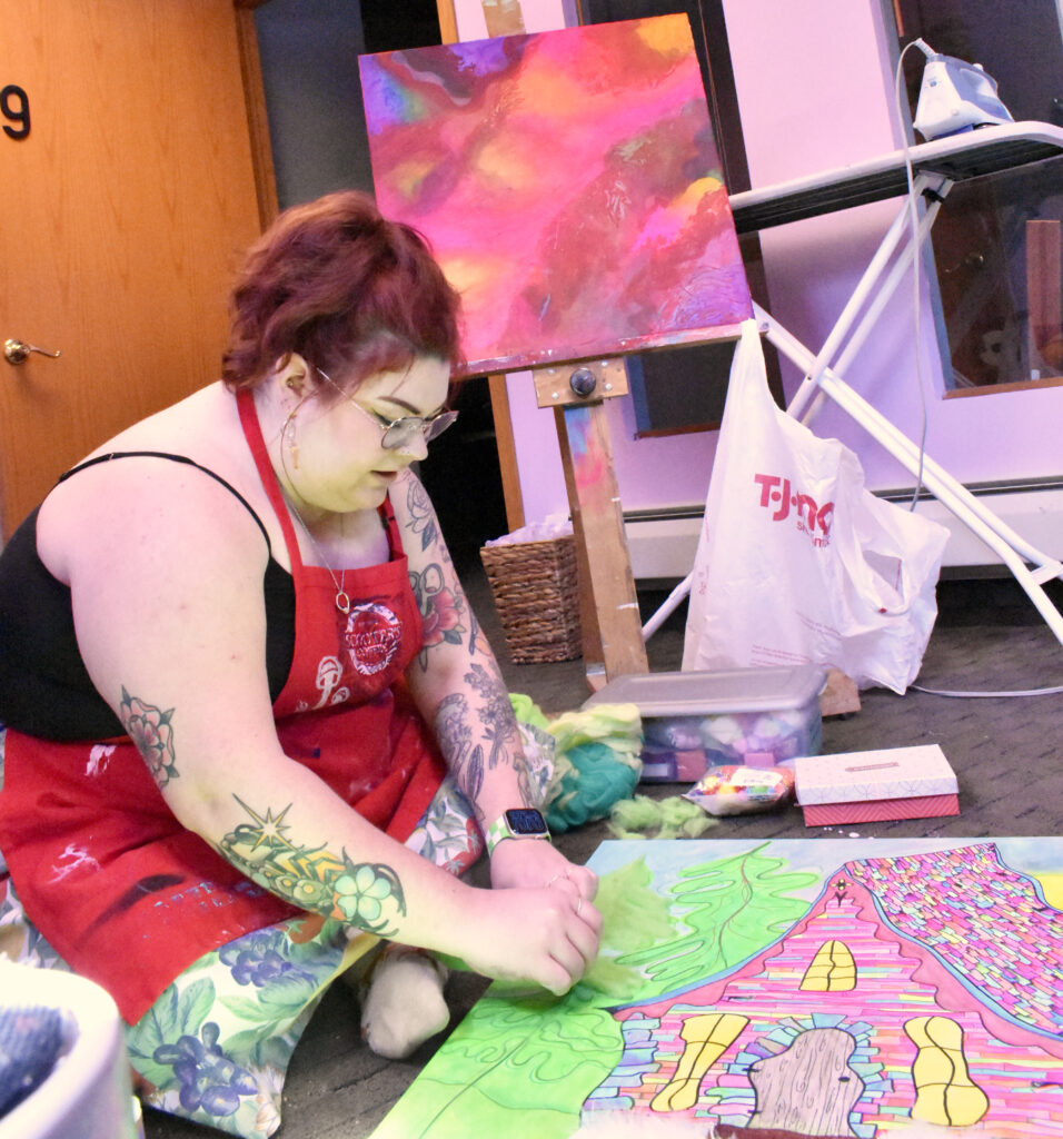 A person with light skin creating an art piece on the floor.