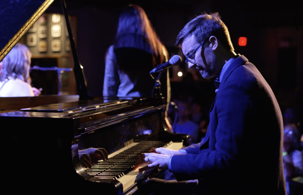 A man sitting at a piano in a dimly lit room.