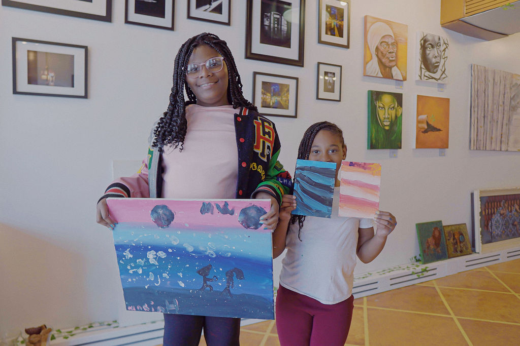 Two children holding paintings they made