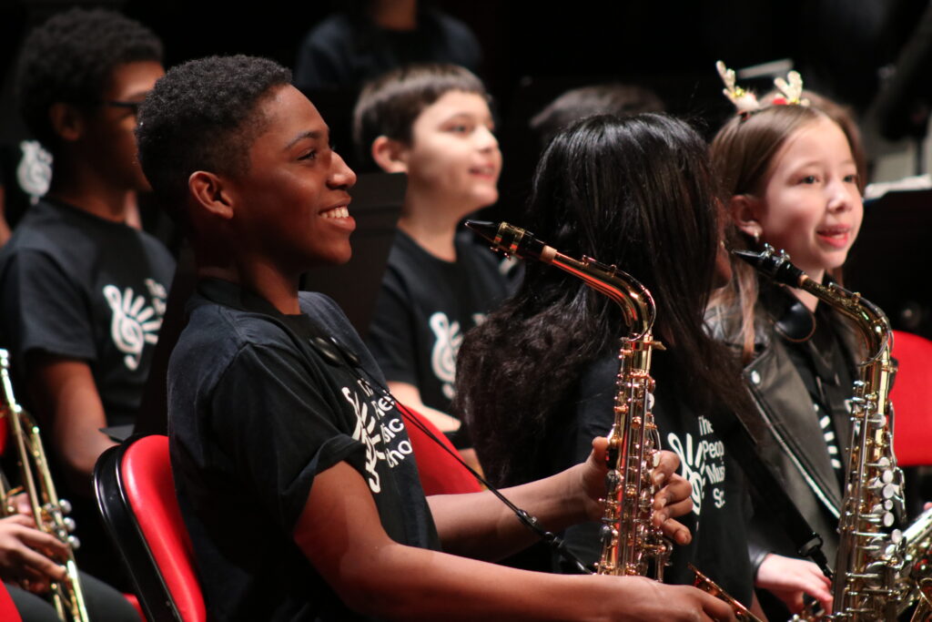 Young musicians playing saxophones sitting together and smiling