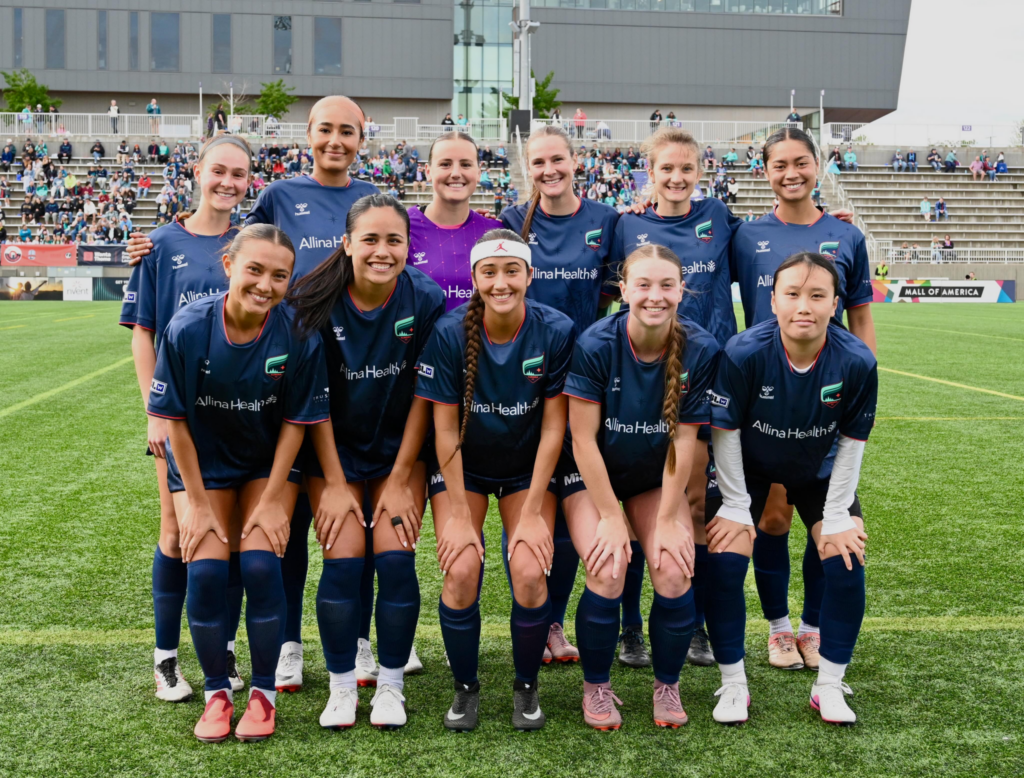 A soccer team smiling and posing on a field