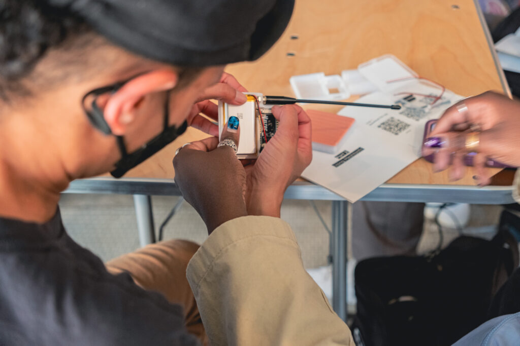 Twp people's hands assembling a small technological device on a table.