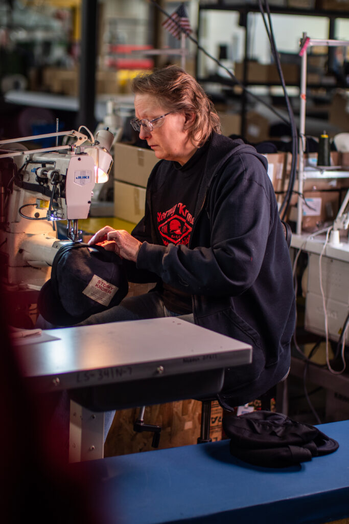 A person sitting at a sewing machine as they made a brimmed cap.