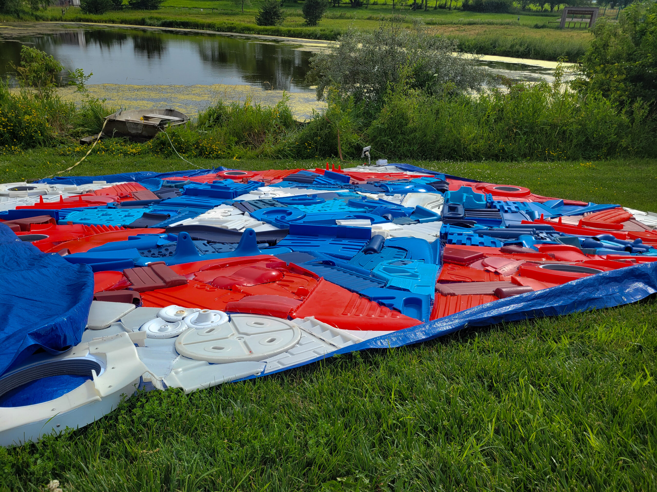 Old cut up plastic pieces in blue, red, and white from toys and beds come together as a large quilt pattern block