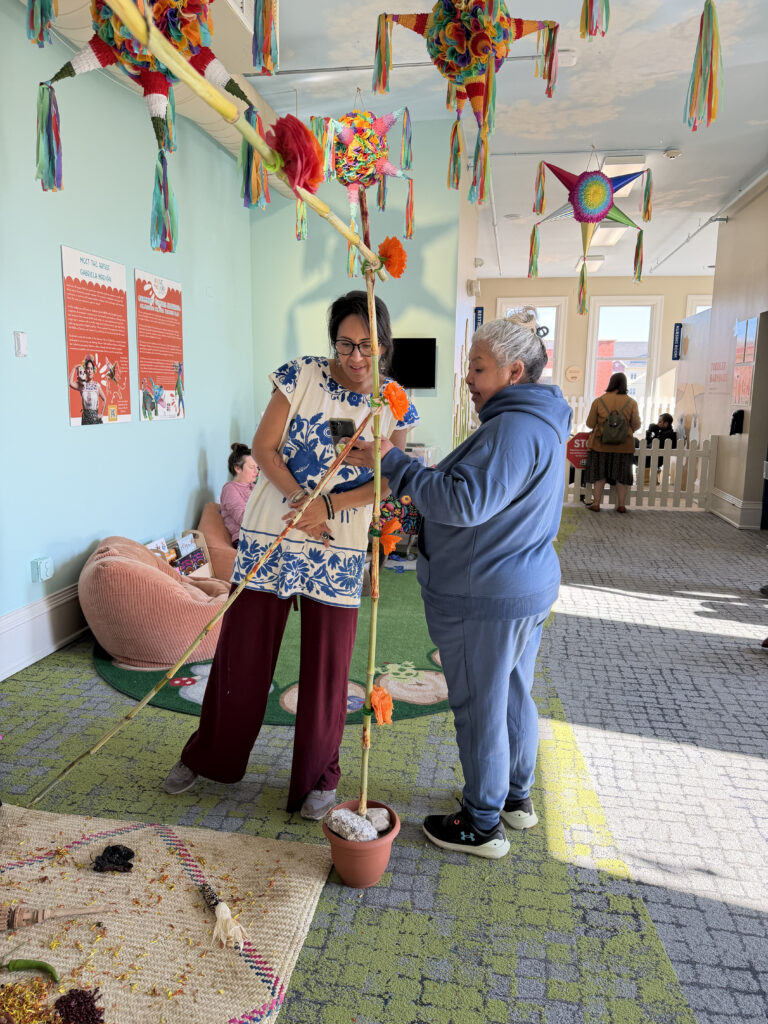 Two people with medium skin tone in a colorfully decorated room putting together a pole.
