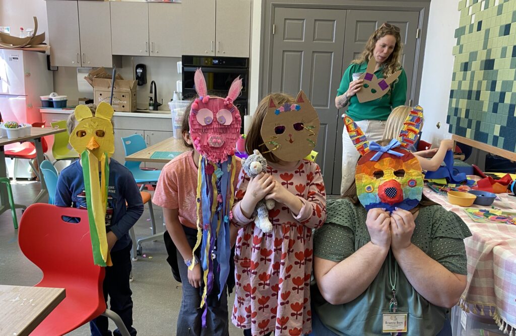 Children posing with colorful, handmade masks.