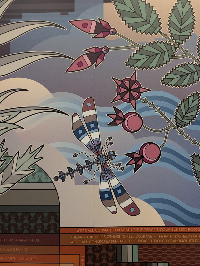 A closeup of a mural depicting a dragonfly, water, and plants.