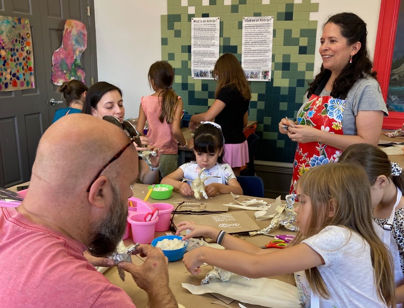 Adults and children creating art around a table indoors.
