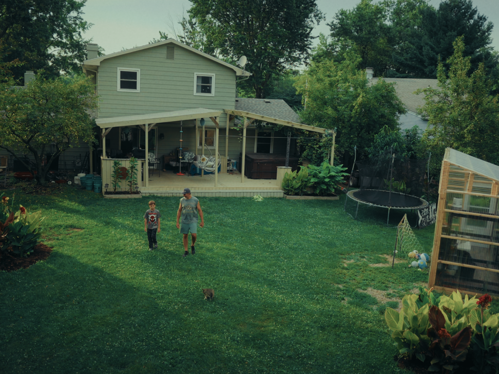 A child and a man walking in a backyard.