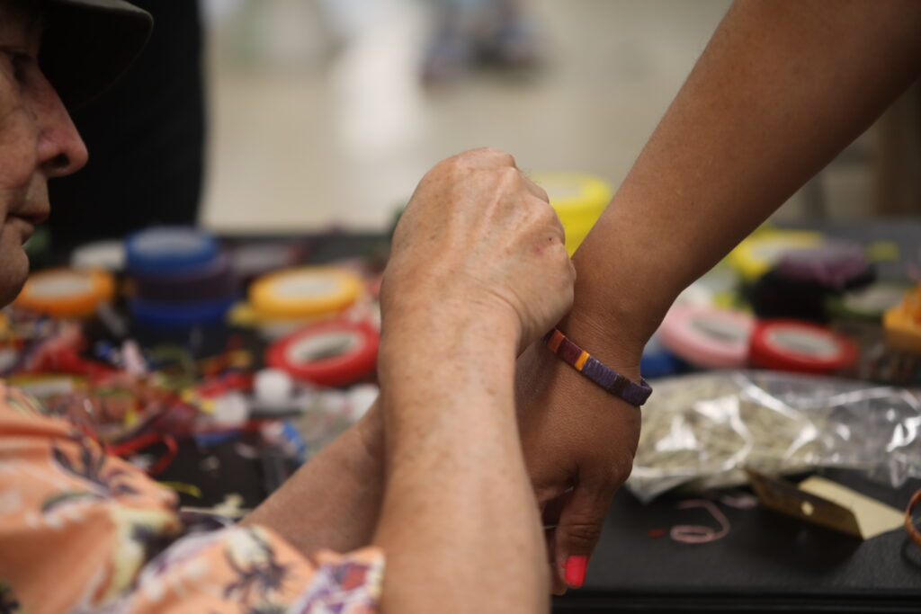 A person helping secure a handmade bracelet to someone's wrist.